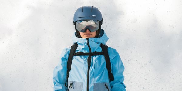 Person in blue ski gear with helmet and goggles in snowy setting.
