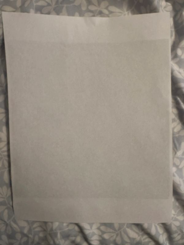 alt="Blank gray paper sheet resting on patterned fabric background with subtle lighting gradients"