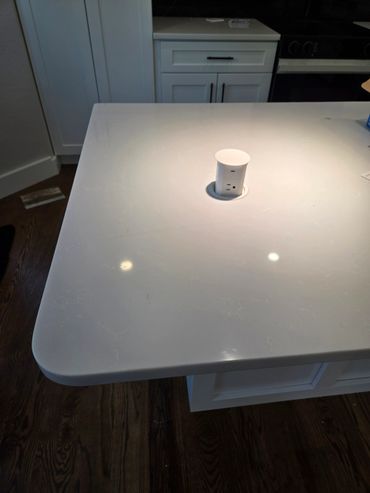 Modern kitchen island with built-in pop-up power outlet on white countertop.