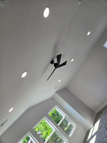 Modern living room ceiling with recessed lights and a sleek black ceiling fan.