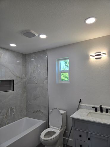 Modern bathroom with marble tiles, white toilet, and vanity.