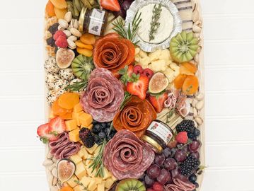 A vibrant charcuterie board with an assortment of fruits, meats, cheeses, and nuts.