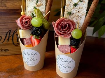 Two elegant charcuterie cups with fruits, cheese, and crackers.
