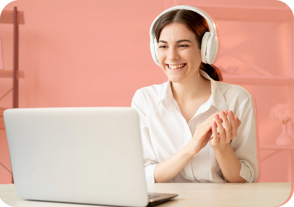 A woman with headphones smiles at her laptop due to positive learner experience during testing.