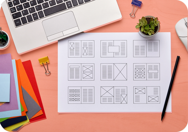 Wireframe sketches spread out beside a laptop and colorful notes, symbolizing quick prototyping.