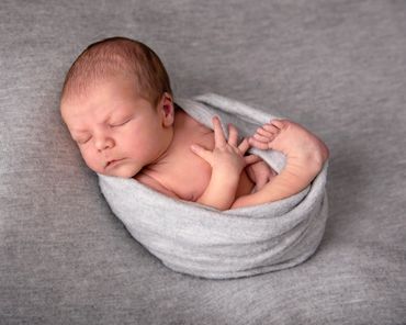 sleeping newborn wrapped in grey