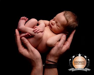 award winning image of sleeping baby cradled in his Fathers hands