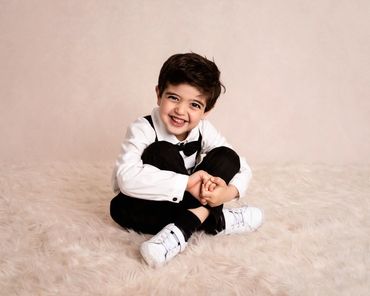 young boy sat cross legged on a cream rug