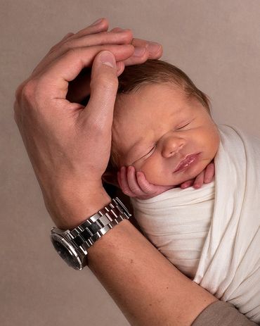 sleeping newborn boy in fathers arm