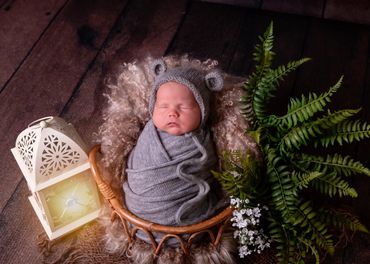 newborn baby in woodland basket with a lantern