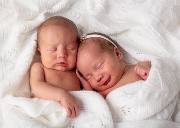 sleeping newborn twins holding each other