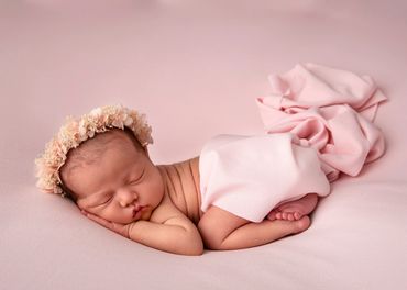 sleeping newborn girl in a flower halo in tushie up pose, resting her cheek on her hand