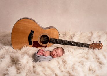 newborn baby boy on fur rug with a guitar