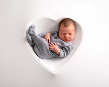 newborn boy asleep in a white heart silhouette bowl