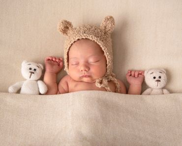 sleeping newborn in bear had with two teddybears