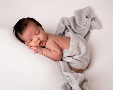 newborn with lots of hair asleep on his tummy