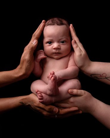 newborn with parents hands on either side