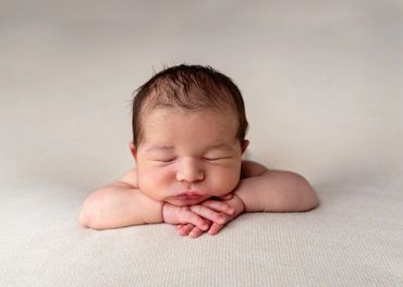 sleeping newborn in chin on hands pose