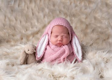 baby dressed as a pink bunny on fur rug