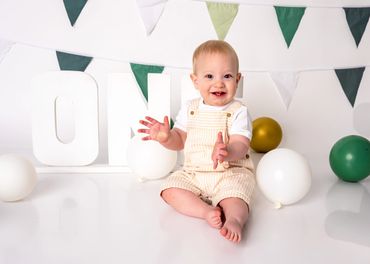 Happy baby celebrating first birthday with balloons and decorations.