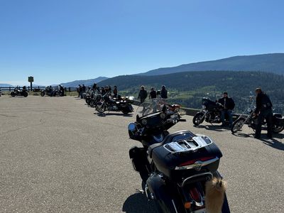 Motorcycles parked at a scenic overlook with people enjoying the view.