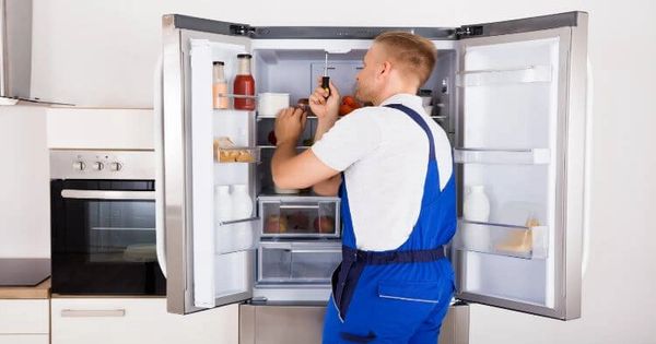 Appliance repair technician repairing fridge
