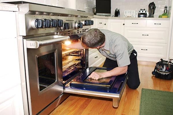 Appliance repair technician repairing oven