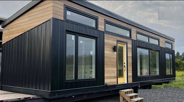 Modern tiny house with black and wood panel exterior and large windows.
