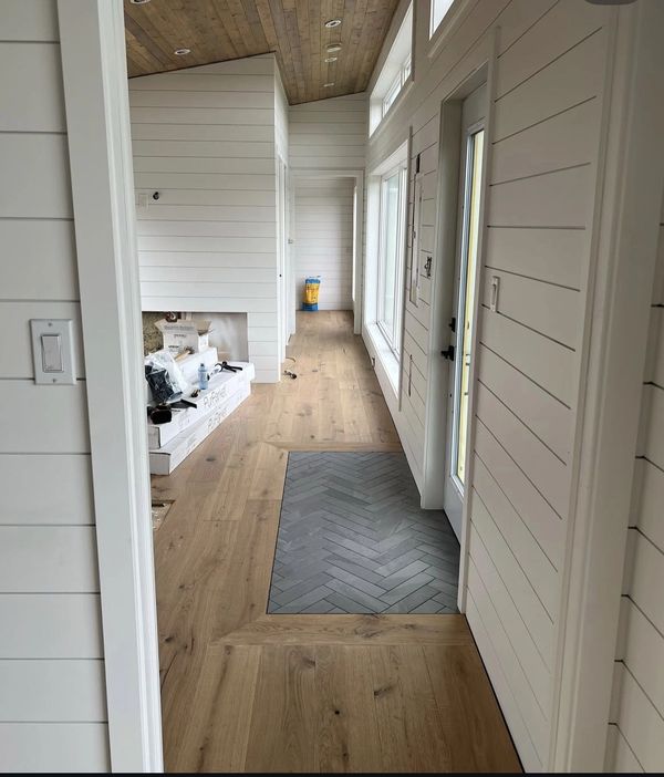 Modern hallway with wood and patterned tile flooring under a wooden ceiling.