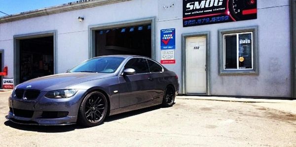 Gray BMW parked outside a smog check shop.