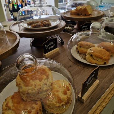 Various pastries and scones on display under glass domes.