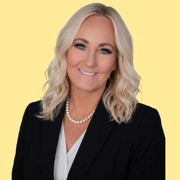 Professional woman with blonde hair, wearing a black blazer and pearl necklace, smiling.