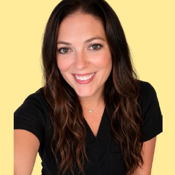Smiling woman with long brown hair wearing a black top against a yellow background.