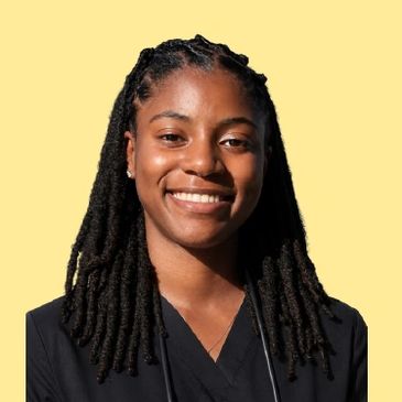 Smiling woman with dreadlocks against a yellow background.