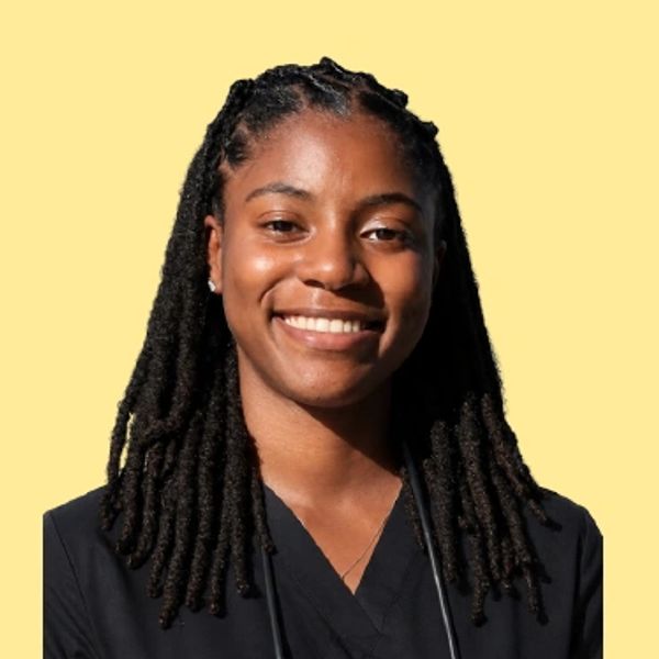 Smiling woman with dreadlocks against a yellow background.