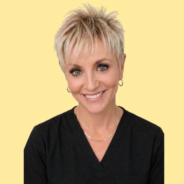 Smiling woman with short blonde hair against a yellow background.