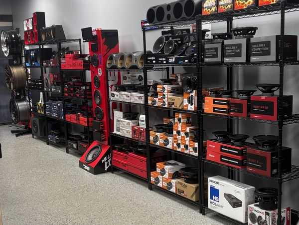 Car audio speakers and accessories on display shelves.