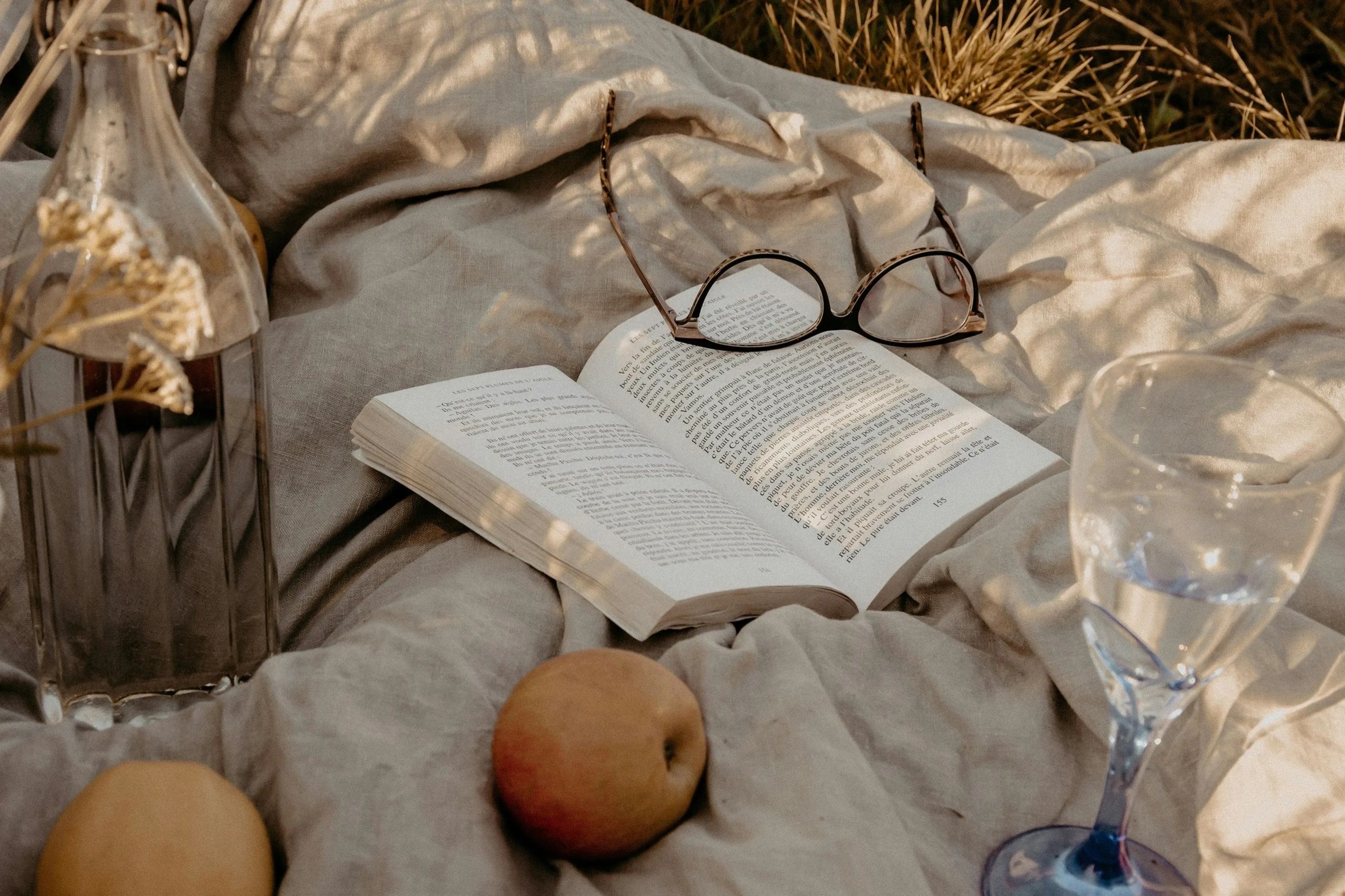 Un livre ouvert avec des lunettes posées dessus lors d'un pique-nique.