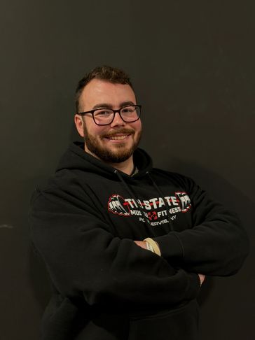 Man with glasses smiling and crossing arms.
