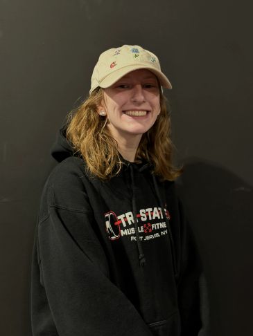 Smiling person wearing a hat and black hoodie.