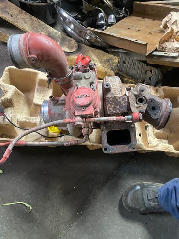 Old red Holset turbocharger on a workshop floor with worn parts around.