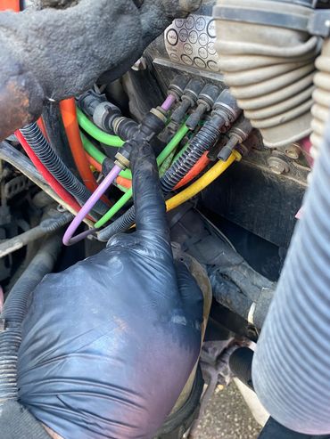 Hand with black glove touching colorful wires connected to a device.
