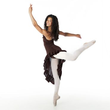 Ballerina in a brown dress gracefully poses en pointe against a white background.