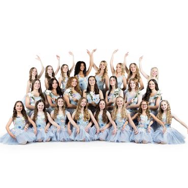 A group of young women in matching blue dresses posing with raised arms.