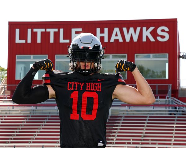Young football player in black and red uniform standing in football stadium by bleachers