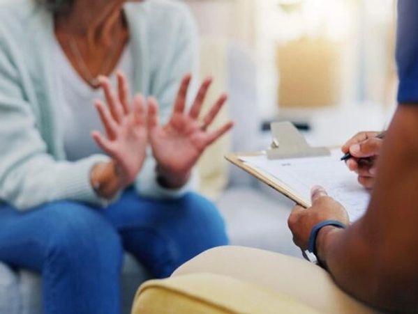 Person gesturing with hands during a conversation with someone taking notes.