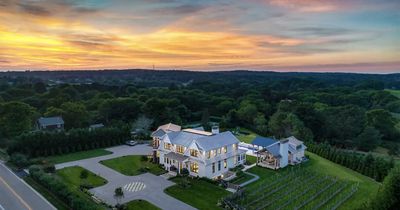 Aerial view of a large estate with expansive sod lawns surrounding the home, driveway, and pool area