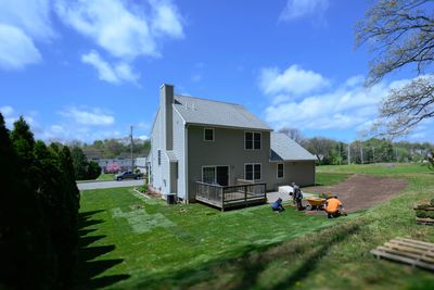 Crew installing sod in the backyard of a suburban home, with fresh rolls being laid on prepped soil.