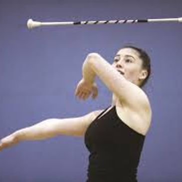 Woman performing baton twirling with focus.