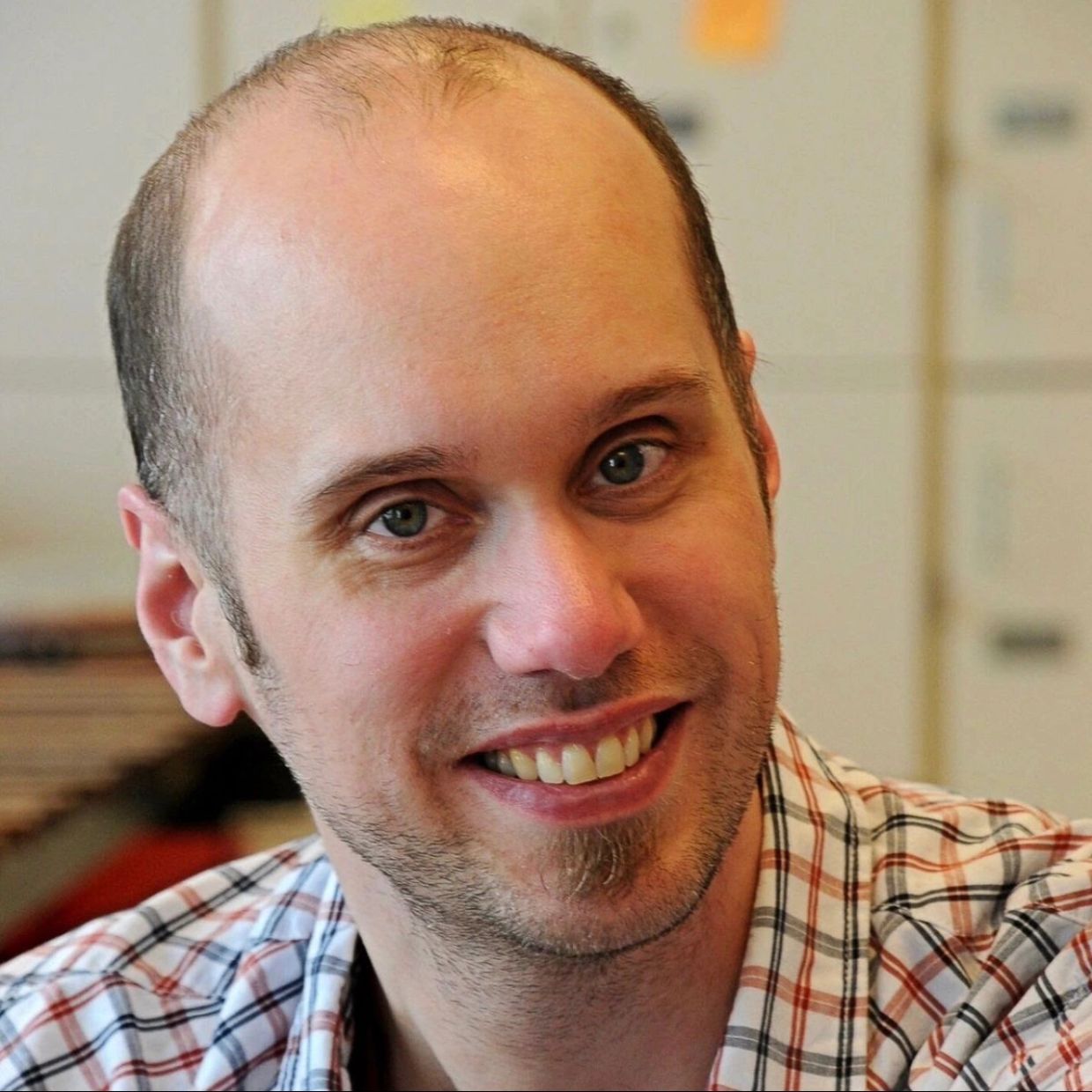 Smiling man with a plaid shirt.